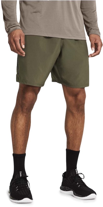 Man met legergroene shorts, zwarte sokken en zwarte sportschoenen