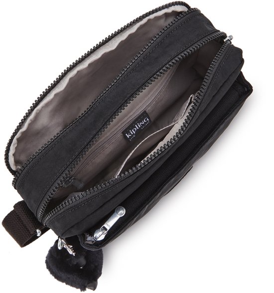 Open zwarte Kipling schoudertas met een aaibare aap-sleutelhanger, die de compartimenten laat zien.