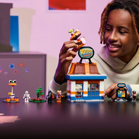 Garçon jouant avec le Restaurant Durrr Burger LEGO, tenant une figurine burger.