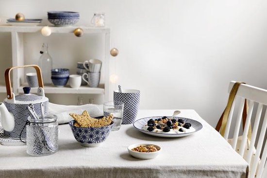 Gedekte tafel met blauw-wit servies, waaronder een theepot, kommen, mokken, en een bord met yoghurt en bessen.
