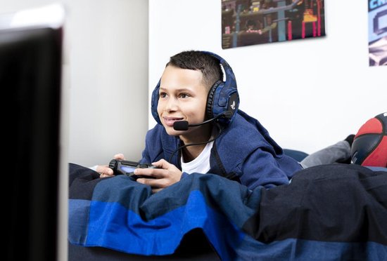 Jonge jongen met blauwe Trust Forze-B gaming headset met camouflagepatroon, spelend op een Playstation.