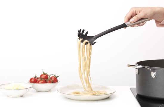 Handen gebruiken een spaghettilepel om spaghetti op een bord te serveren.