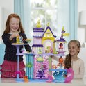 Twee meisjes spelen met een paars, roze en geel My Little Pony kasteel met figuren.