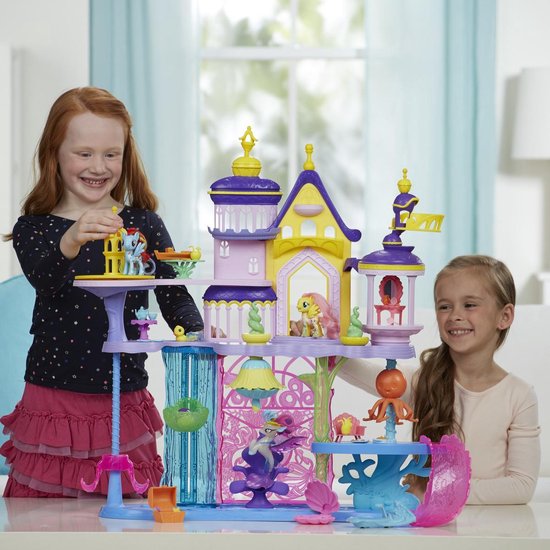Twee meisjes spelen met een paars, roze en geel My Little Pony kasteel met figuren.