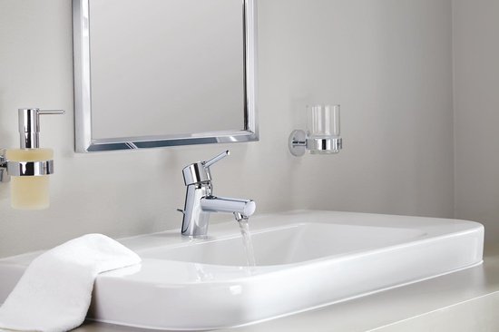Chroom wastafelkraan met lopende waterstraal, bij witte wasbak.
