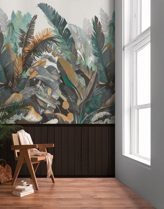 Een houten stoel met witte plaid voor een behang met tropische bladeren en donkerbruine lambrisering.