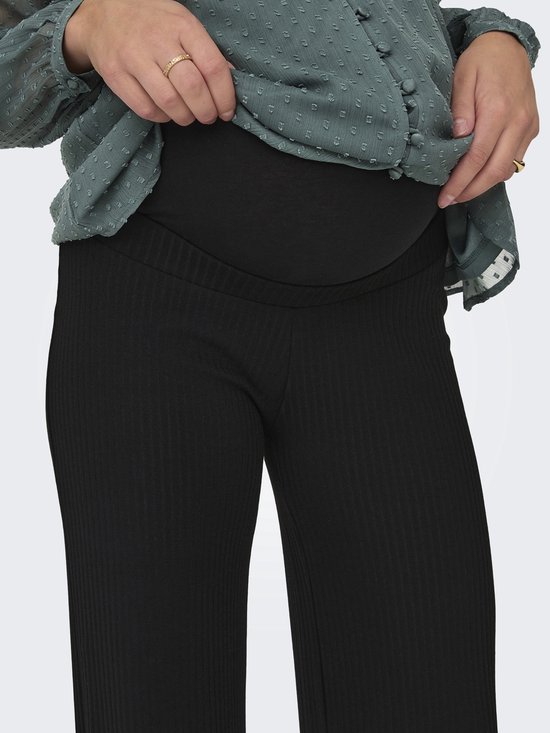 Gedetailleerde close-up van de hoge, elastische zwangerschapsbuikband van een zwarte ribbroek.