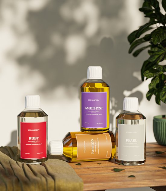 Drie flessen SteamStory wasparfum: "Ruby" (rood label), "Passion" (oranje label) en "Pearl" (grijs label).