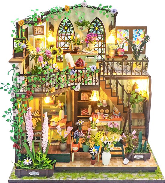 Miniatuur poppenhuis met groene planten, bloemen en verlichting.