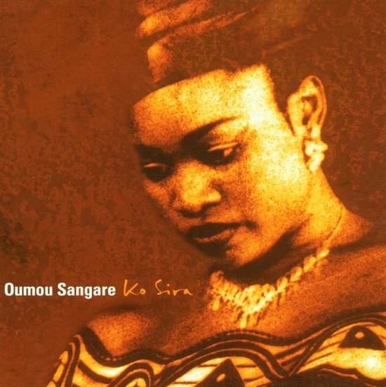 Oumou Sangare met een ketting en een hoofddeksel, met een oranje-bruine tint.