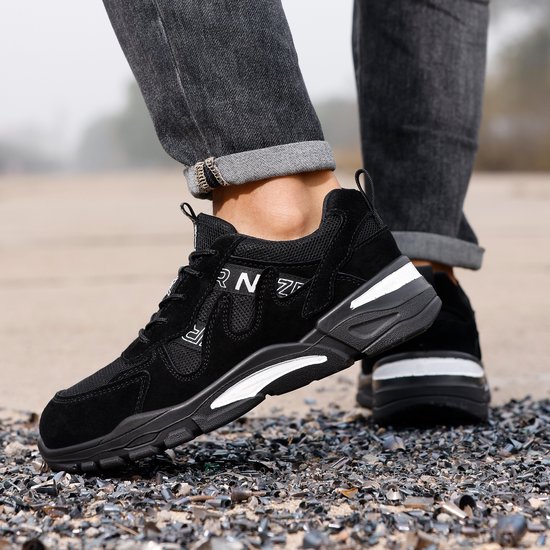 Dichtbij opname van zwarte NezR werkschoenen gedragen met jeans, met witte accenten op de zool.