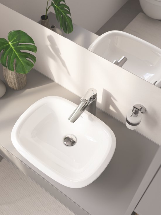 Badkamer met witte wasbak, chromen kraan en zeepdispenser.