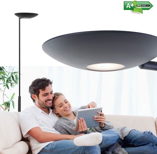 Un couple sur un canapé regardant une tablette, avec un lampadaire noir à côté.