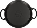 Zwarte braadpan van gietijzer, onderkant met tekst 'Le Creuset Made in France 5.1/2 Qt 5.5L'.