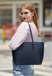 Mannequin portant un sac fourre-tout Eleganci bleu marine sur son épaule, debout à l'extérieur.