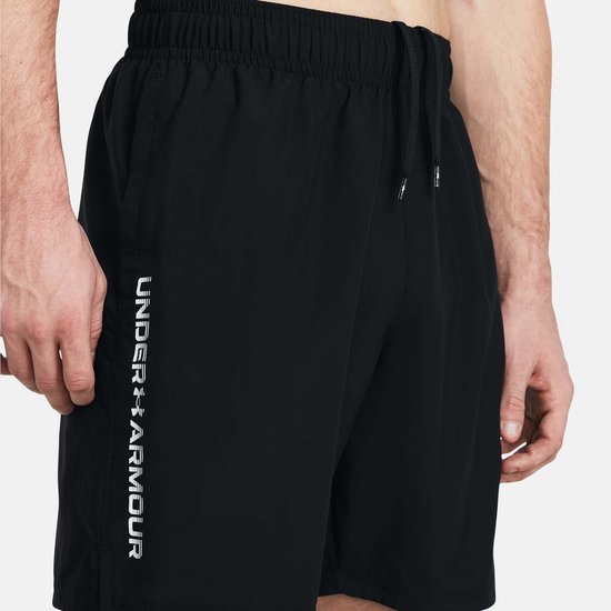 Close-up van een zwart sportbroekje met wit logo op linkerbeen.