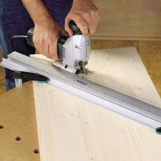 Een persoon gebruikt een wolfcraft decoupeerzaag met een geleiderail om een rechte snede te maken in een houten plank.