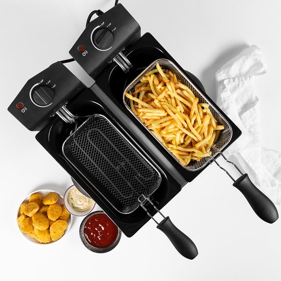 Dubbele frituurpan, gevuld met frietjes en kipnuggets, met dipsauzen ernaast.