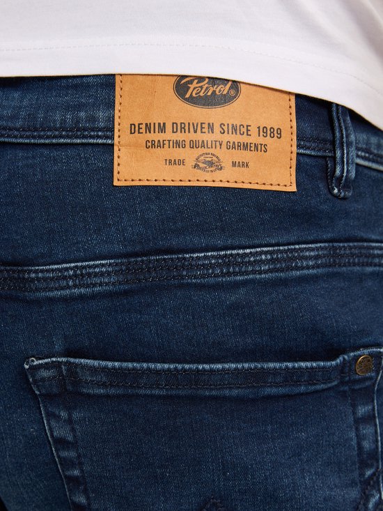 Close-up van het bruine leren merklabel op de achterkant van een donkerblauwe jeans.