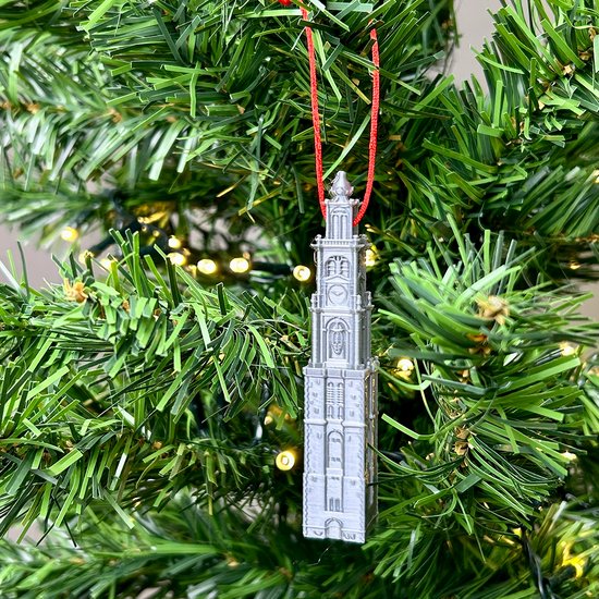 Zilverkleurige kersthanger van de Westerkerk, met rode lus, hangend in een kerstboom.