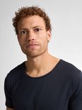 Model met krullend rood haar, sproeten en een donkerblauwe t-shirt met ronde hals.