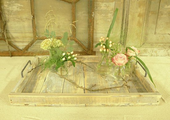 Houten dienblad met roze rozen en groen gebladerte in vaasjes.