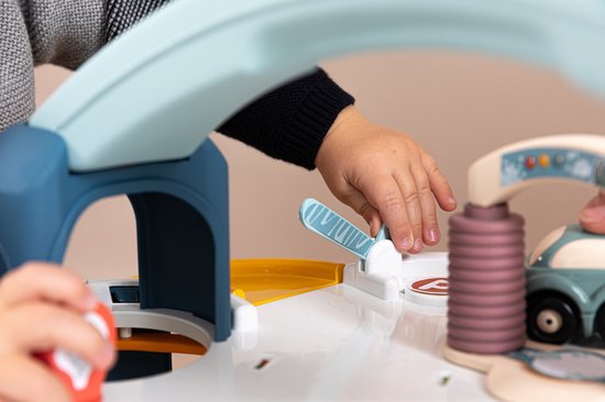 Kindervingers spelen met de Little Smoby speelgoedgarage, met gele glijbaan en auto's.
