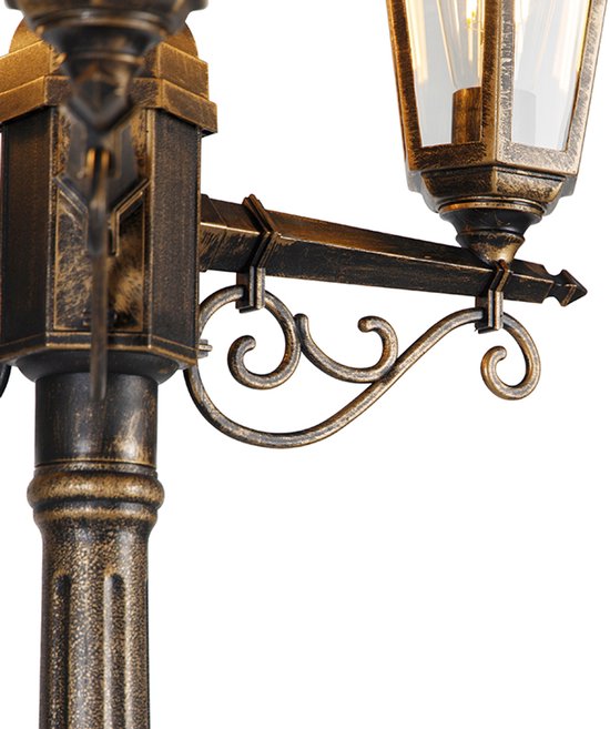 Close-up van de sierlijke, gebogen metalen steunen en een lantaarn van een buitenlamp.