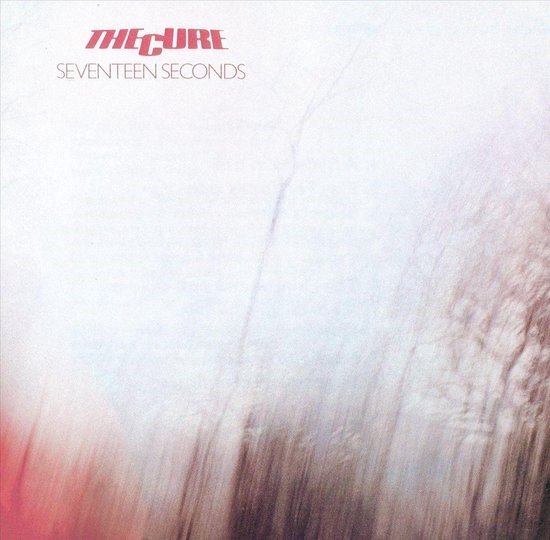 Albumhoes met de titel "THE CURE SEVENTEEN SECONDS" in rode letters. Vage afbeelding van bomen in de herfst.