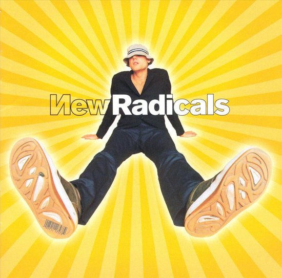 Zanger met pet en donkere kleding, zittend op de grond met gespreide benen en grote sneakers, tegen gele zonnestralen. Tekst: New Radicals.