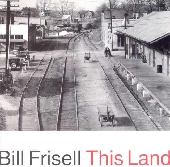 Zwart-wit foto van een treinstation met Bill Frisell This Land in grote letters onderaan.