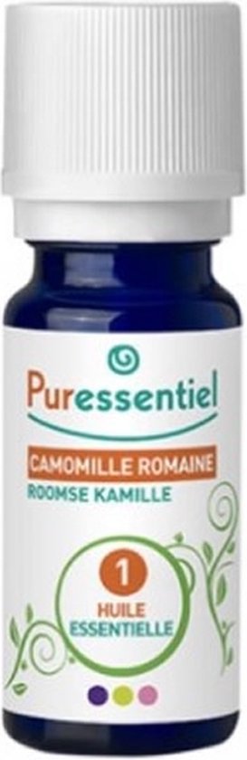 Flesje Puressentiel Roomse Kamille etherische olie in donkerblauw glas, met groene plantendecoratie.