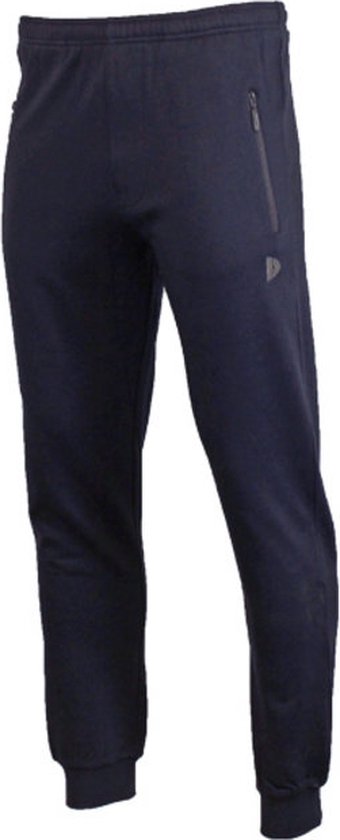 Jonge man in donkere joggingbroek en wit T-shirt, zittend op een reling met bal.