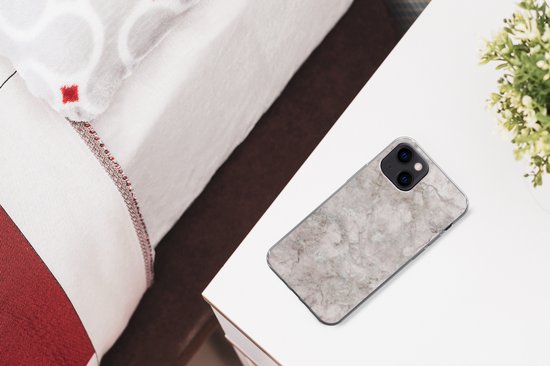 iPhone 13 hoesje met marmerprint op een nachtkastje, naast een bed.
