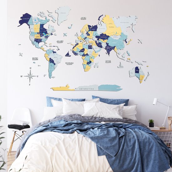 Een houten wereldkaart hangt boven een opgemaakt bed met blauwe dekens.