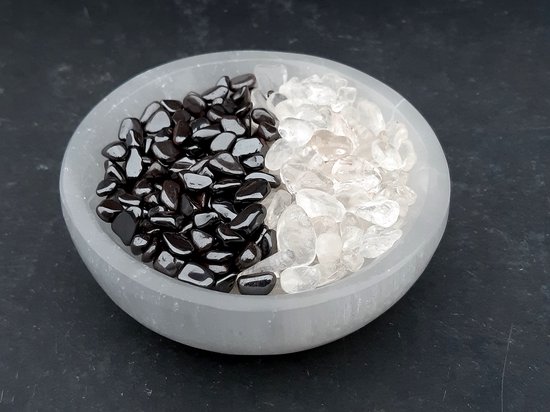 Mélange de pierres précieuses de charge (cristal de roche) et de décharge (hématite) dans un plat en sélénite