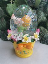 Paasdecoratie ovale schudbol van 12.5 cm hoog met vrolijk konijntje en versierd paasei op een Geel emmertje met lentebloemen en tekst Happy Easter