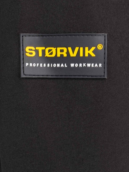 Zwart label op een zwarte jas met "STØRVIK PROFESSIONAL WORKWEAR" in geel.