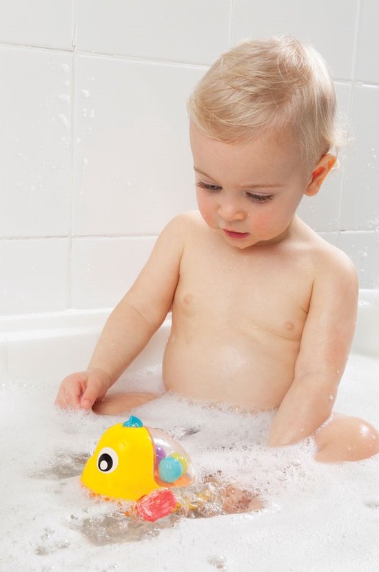 Een baby zit in bad en speelt met een geel badeend visje dat rondspat.