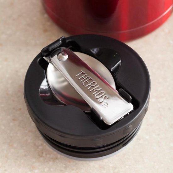 Gros plan sur le couvercle d'un contenant alimentaire Thermos rouge avec une cuillère pliable.