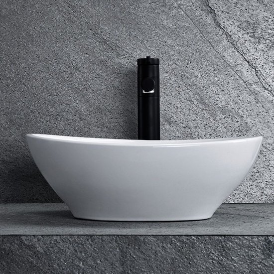 Vue latérale d'un lavabo blanc ovale à poser avec robinet noir.