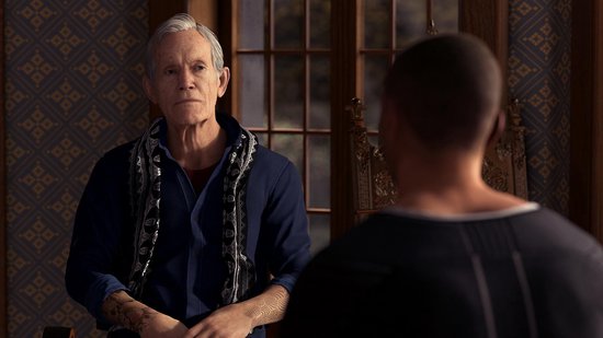 Oudere man met grijs haar, draagt een donkerblauw shirt en een sjaal met print.