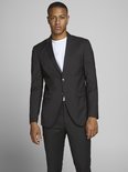 Jonge man met donkere huid draagt een zwart Jack & Jones blazer over een wit T-shirt en een zwarte broek.