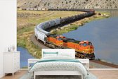 Behang - Fotobehang Een oranje gekleurde trein - Breedte 420 cm x hoogte 280 cm