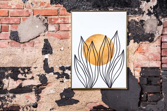 Abstract schilderij met gouden cirkel en zwarte bladeren in een gouden lijst, tegen een bakstenen muur.