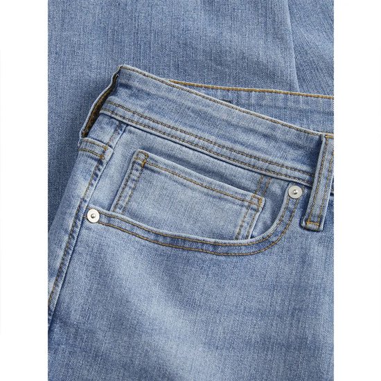 Detail van de voorkant van een lichtblauwe jeans, met zakken en stiksels.