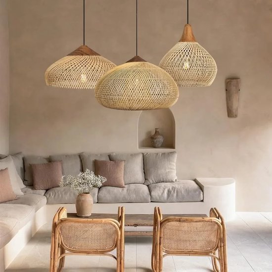 Drie rieten hanglampen met houten bovenkanten hangend boven een modieuze woonkamer met bank en rotan stoelen.