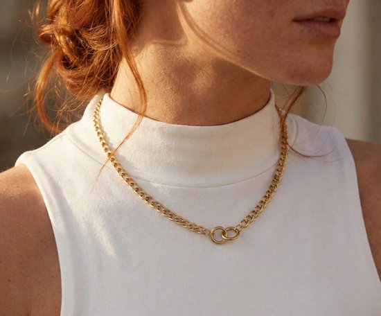 Chaîne à maillons dorée avec des anneaux connectés portée par une femme aux cheveux roux, col roulé blanc.