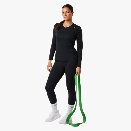 Model draagt een zwarte longsleeve top en zwarte legging, met witte sokken en sportschoenen.