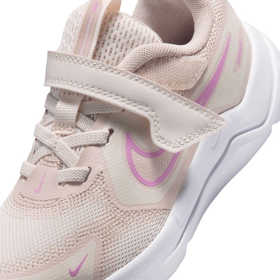 Lichtroze sneaker met roze Nike logo, klittenbandsluiting en de tekst 'RUNNING' op de zijkant.